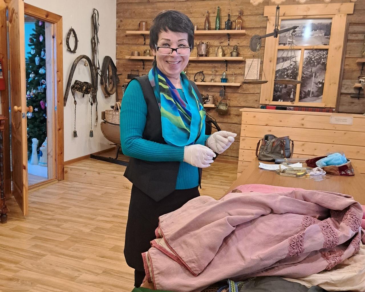 Olga Zaharova tutkii Aunuksen museossa säilytettäviä naisten pukuja. Kuva: Aunuksen museon VKontakte-sivu